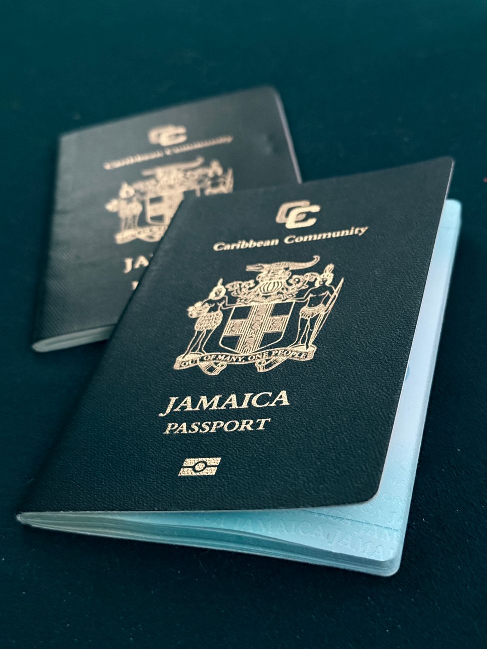 two jamaican passports on a blue surface